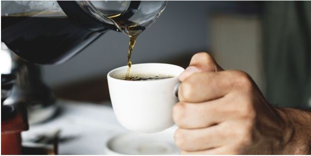 Coffee being poured in to a white cup held in a hand. If spilt cleaning could be difficult
