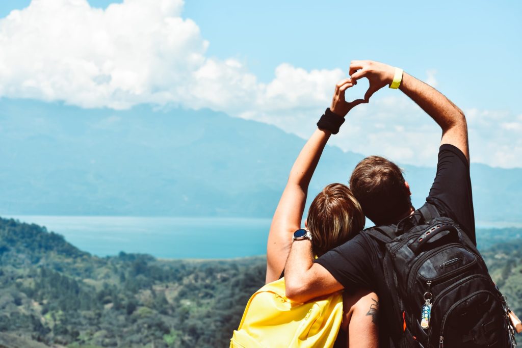 Couple making a love shape with theirs hands on a mountain having a weekend break