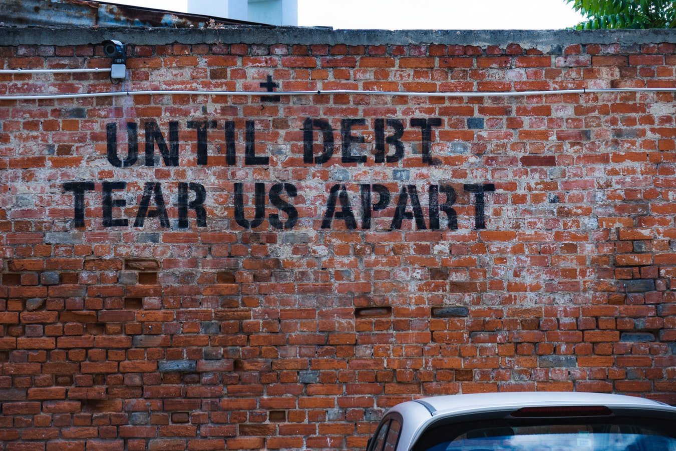 Brick wall with the word Until Debt Tear Us Apart written on it in black paint - finance