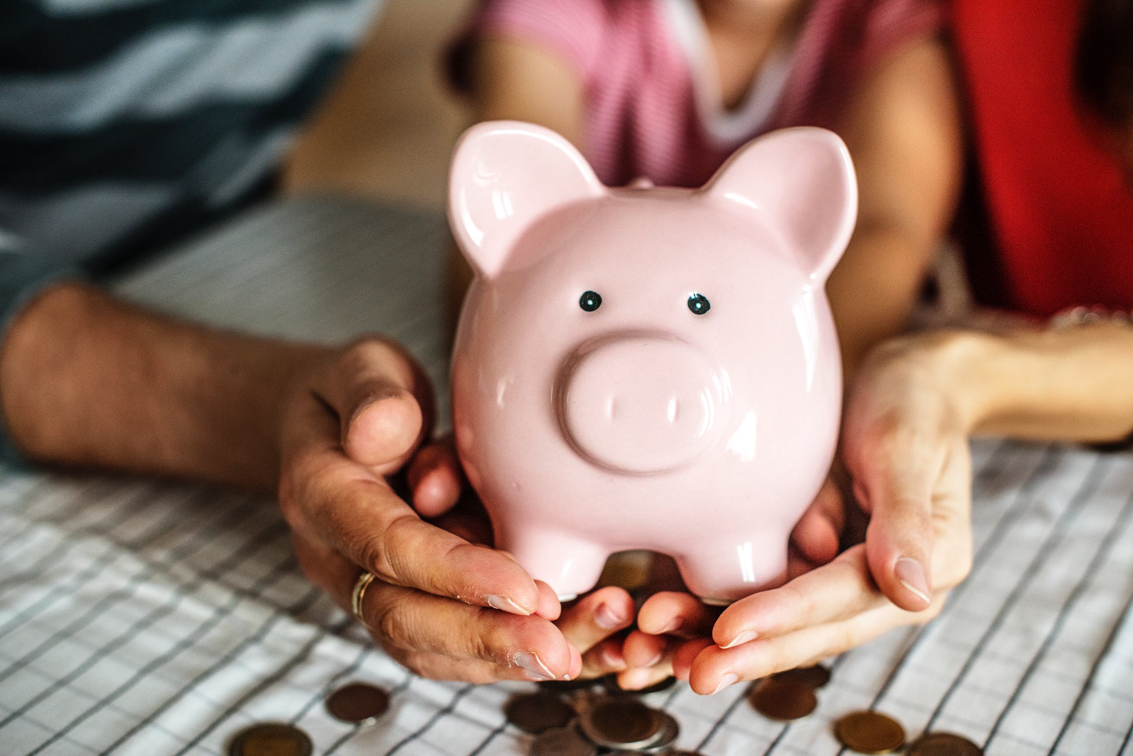 Pink Piggy bank with Dad, Mum and Daughter holding onto the bottom of it. With coins falling out - finance