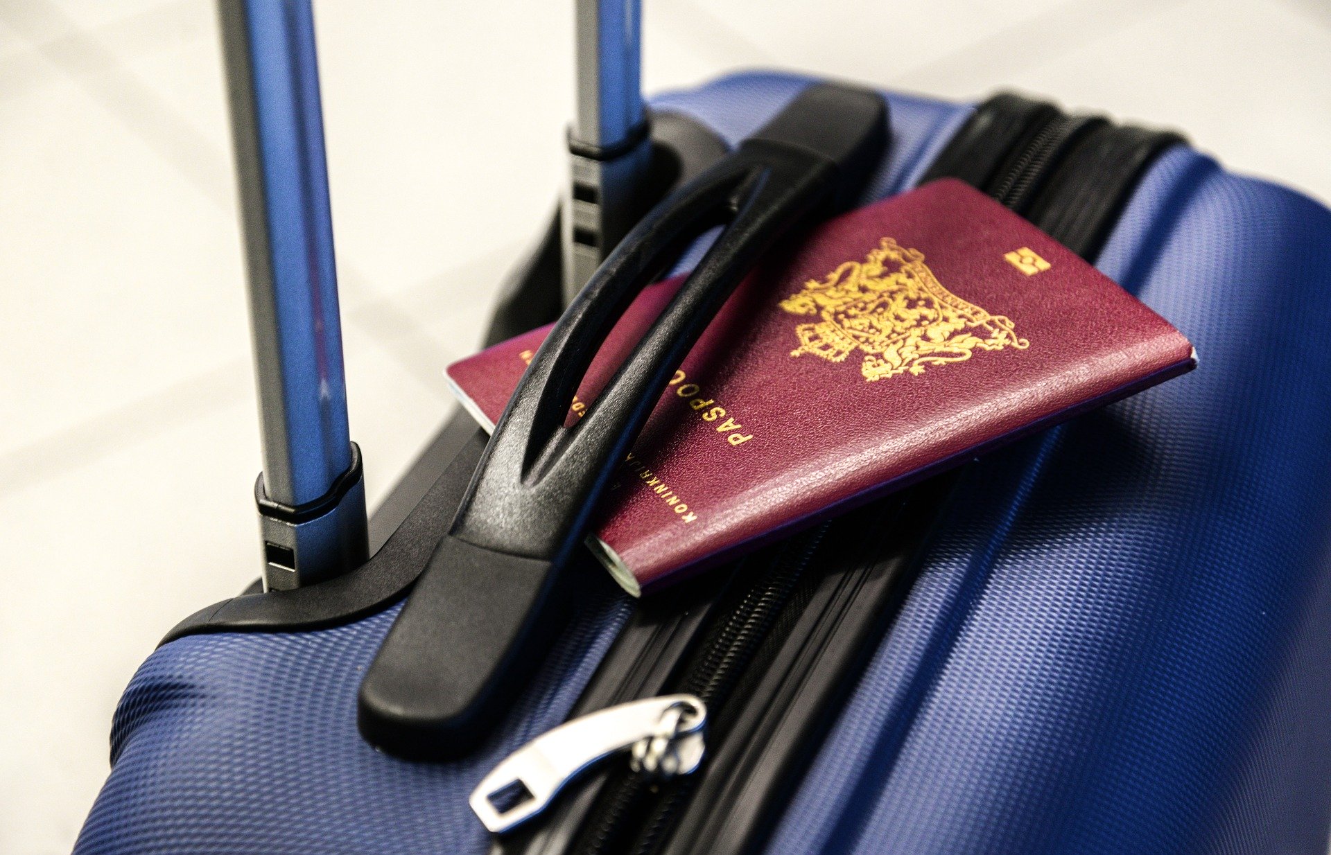 Dark blue suitcase with a passport in the handle. School Skiing Trip