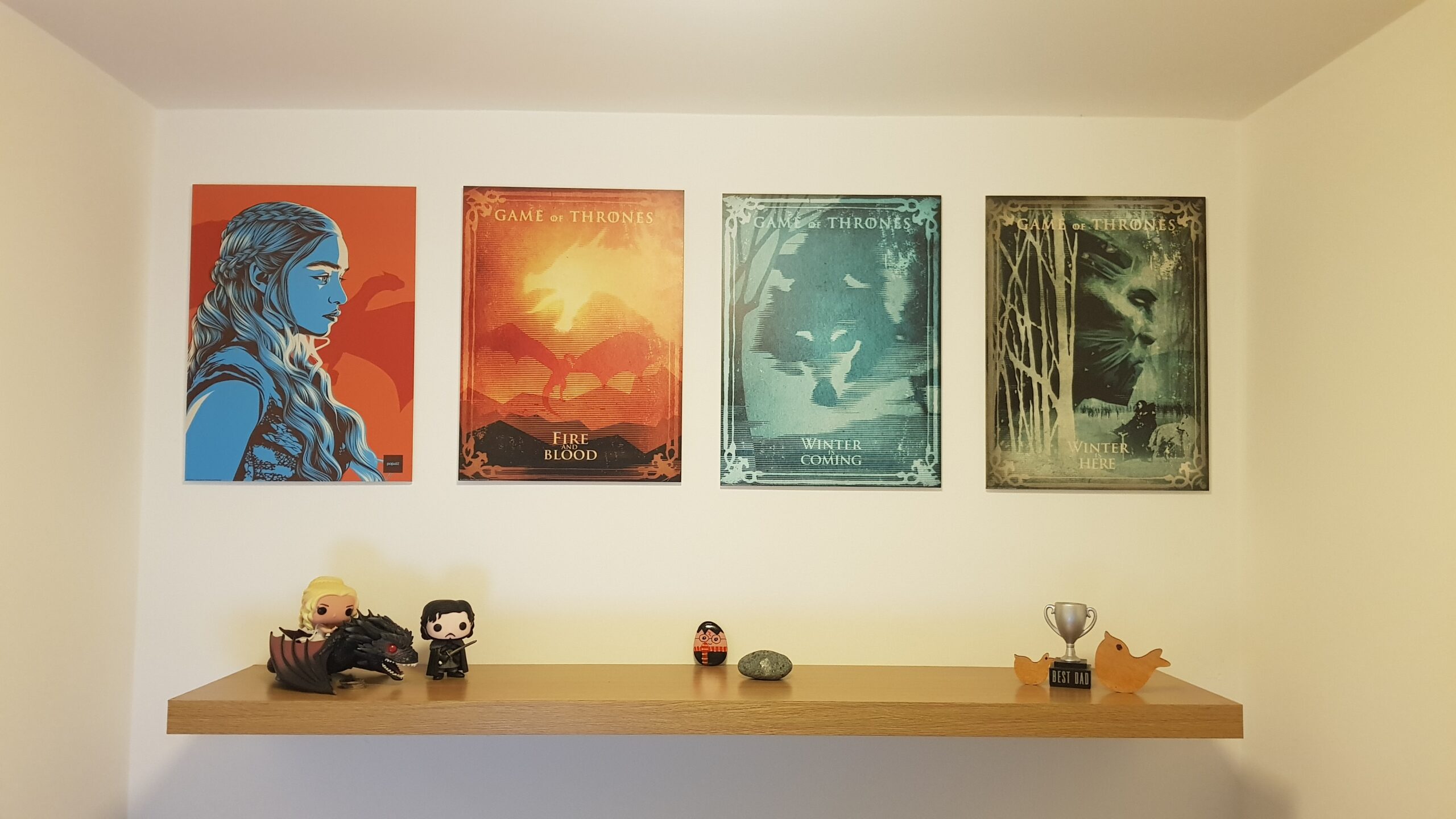Game of Thrones Poster hanging above a shelf with a couple of pop characters for declutter