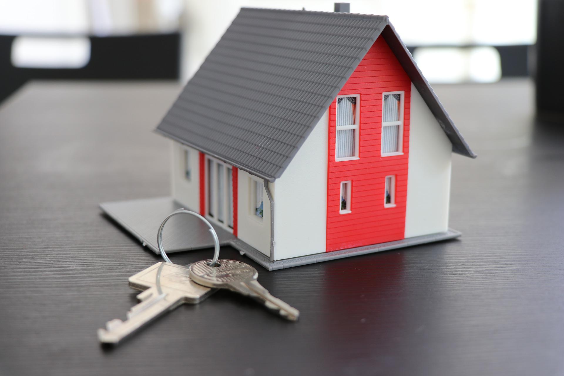 Minitue house with a set of house keys on a desk for Buying a House