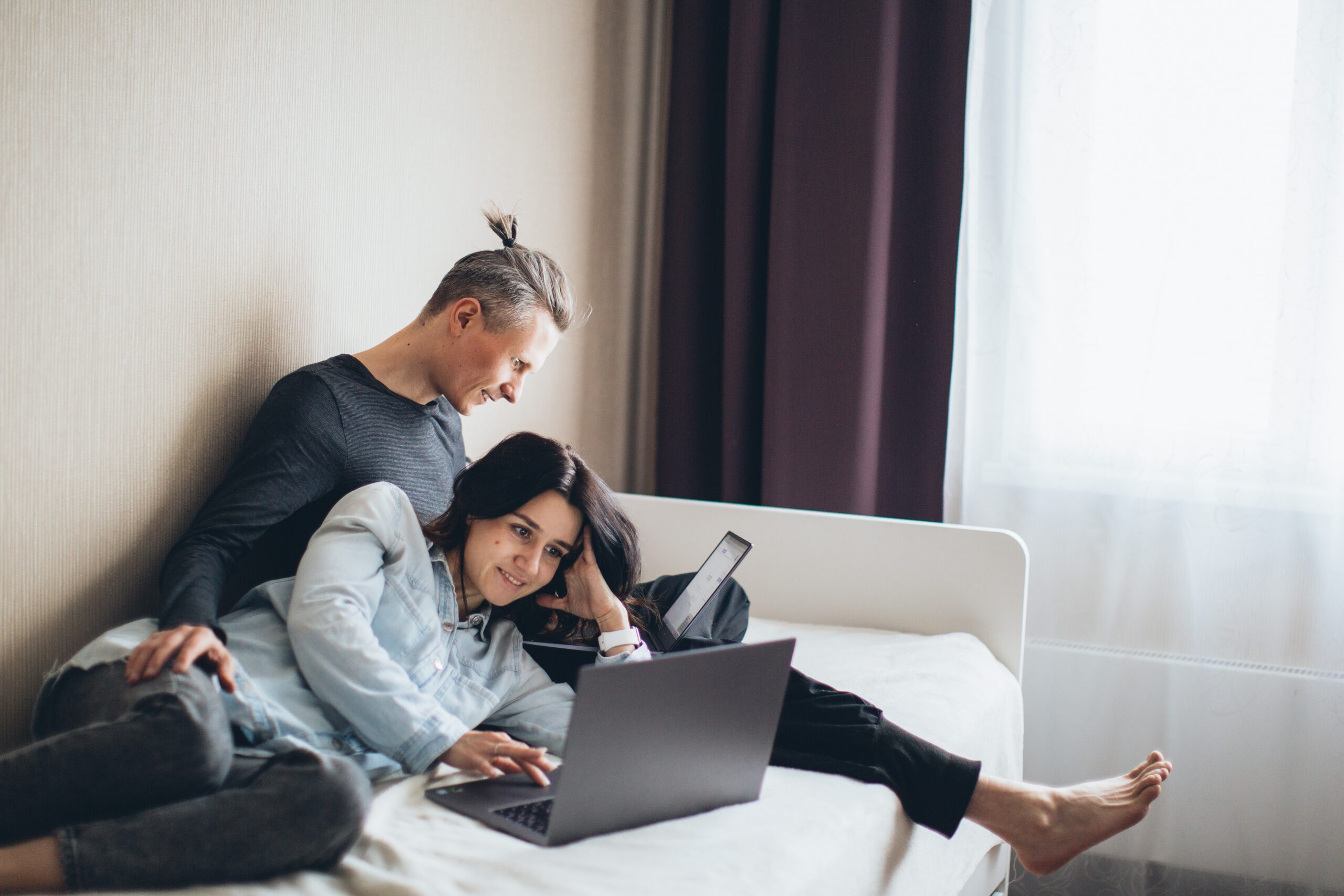 Couple on a bed watching a laptop for Entertained