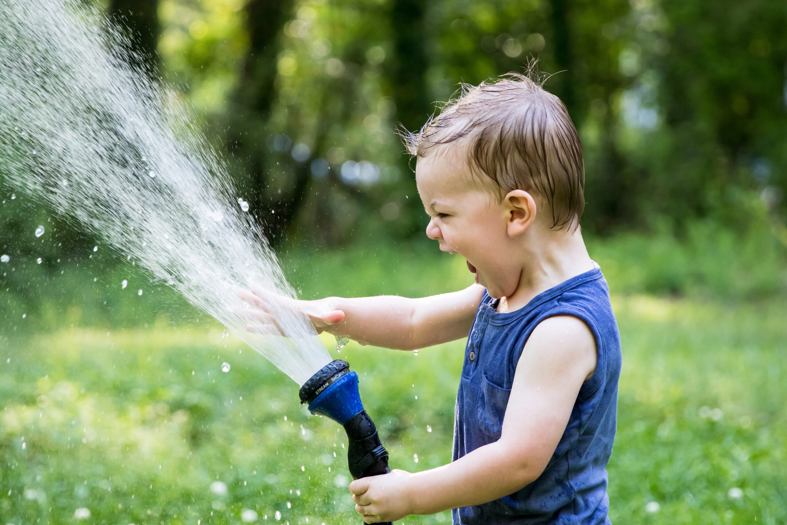 Toddler playing with a hose
